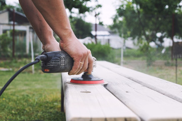 man polishes the board on the bench. man repairing bench in the garden
