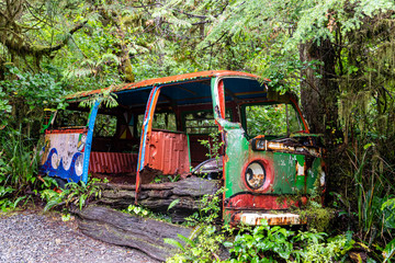 Abandoned camper van with psychedelic paint work photographed in a forest in British Columbia, Canada