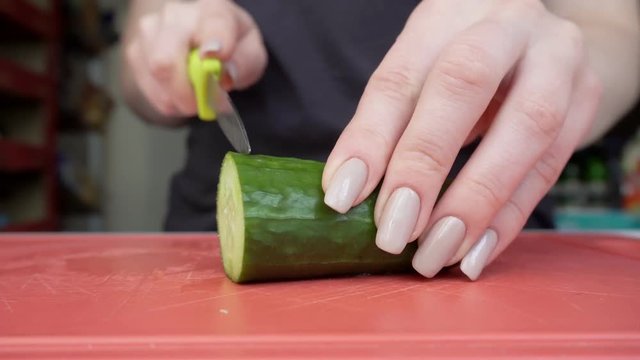 Woman cuts cucumber into salad. Proper and healthy food. Close-up