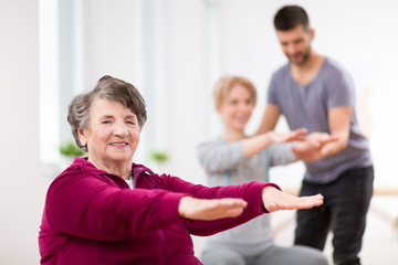 Senior lady exercising during group physiotherapy at rehabilitation center
