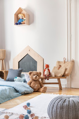 Pouf, carpet, toys, bags and bed with blue bedding in stylish little boy's bedroom, real photo