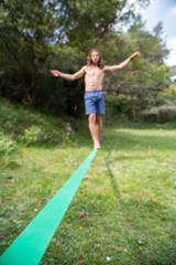  Defocused young man with naked torso doing slackline in field on summer day