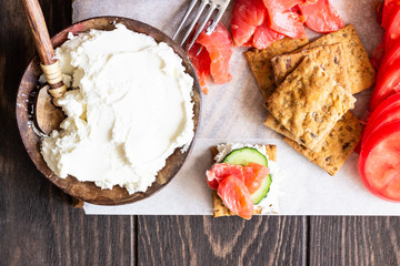 Healthy breakfast ingredients: smoked salmon, liver pate, cucumber, tomato, avocado, mozzarella and cream cheese, multigrain crackers.  Breakfast served with coffee and milk. Healthy snacks.