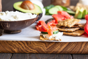 Healthy breakfast ingredients: smoked salmon, liver pate, cucumber, tomato, avocado, mozzarella and cream cheese, multigrain crackers.  Breakfast served with coffee and milk. Healthy snacks.