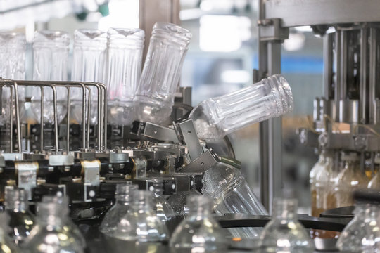 Plastic bottles inside industrial machine conveyor line or belt preparing for filling with drink. Water and juice bottling plant