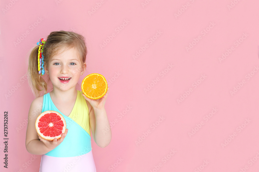 Wall mural happy little girl having fun , holding two fresh halves of orange and grapefruit . concept of health