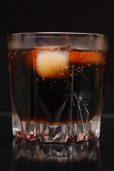 A steaming glass of cold thirst-quenching red-brown drink with ice cubes.