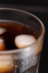 A steaming glass of cold thirst-quenching red-brown drink with ice cubes.