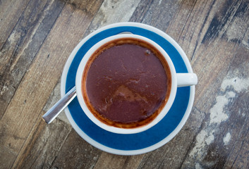Delicious, thick Italian hot chocolate in blue and white cup on wood table