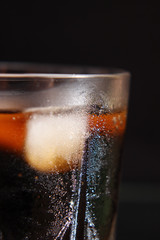 A steaming glass of cold thirst-quenching red-brown drink with ice cubes.