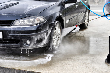 Cleaning Car Using High Pressure Water. Man washing his car under high pressure water in service