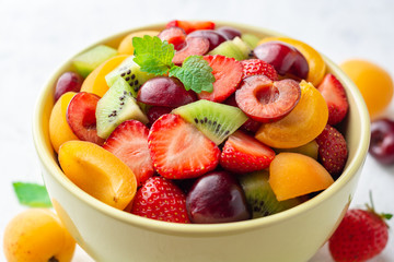 Healthy fresh fruit salad in bowl on gray concrete background. Selective focus.
