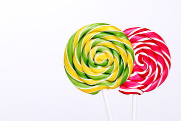 Fototapeta na wymiar Red and green lollipops on white background. Lollipops with stripes. Round sweet candies on a white sticks. Copy space