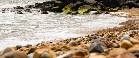 Pebbles and rocks sea defences on coast ocean
