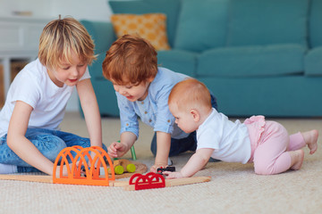 cute kids, siblings playing toys together on the carpet at home