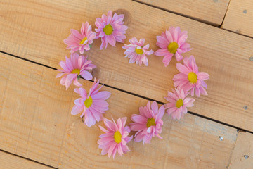 Beautiful flowers in heart shape on wooden background