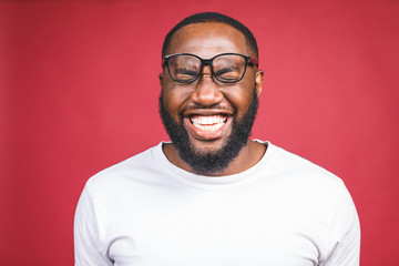 Portrait of African American man laughing isilated over red.