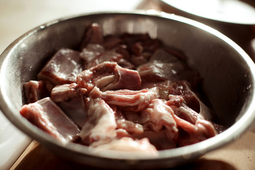 pieces of raw meat lie in a steel bowl, ready to cook