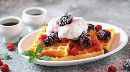 Belgian waffles with ice cream, mint and frozen raspberries and blackberries. Tasty breakfast.
