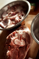 pieces of raw meat lie in a steel bowl, ready to cook