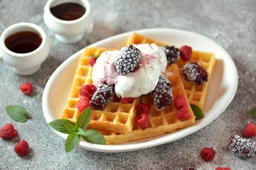 Belgian waffles with ice cream, mint and frozen raspberries and blackberries. Tasty breakfast.