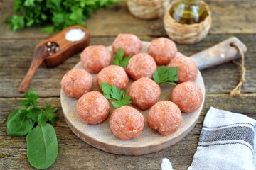 Raw meatballs on a wooden board.
