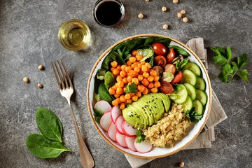 Healthy vegetarian salad with chickpeas, quinoa, cherry tomatoes, cucumber, radish, spinach, avocado and parsley. Ketogenic diet. Top view. 