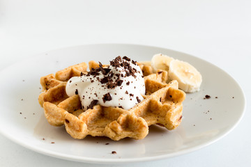 Delicious homemade oatmeal waffle with creamy natural yogurt, honey, banana and chopped chocolate