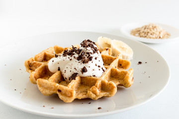 Delicious homemade oatmeal waffle with creamy natural yogurt, honey, banana and chopped chocolate