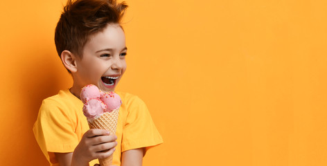 Baby boy kid hold strawberry pink ice-cream in waffle cone happy laughing looking at the corner on...