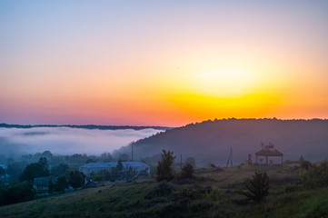 Foggy morning in the village on the river bank