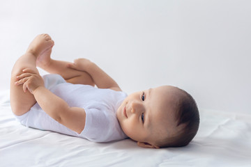 6-month baby having fun in white bedding. Cute baby lying on bed. Family, new life, childhood...