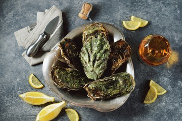 Closed oysters in nickel silver dish with lemon and champagne. Top view.  Copy space. 