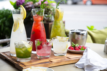 Summer soft drinks, a set of lemonades. Lemonades in jugs on the table, the ingredients of which they are made are arranged around.