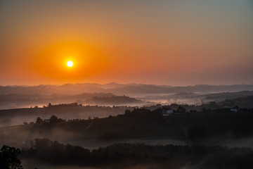Red sunrise over foggy piedmont vineyards of Langhe Roero and Monferrato. Barolo wine tasting area