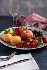 Healthy fruit platter, strawberries, apples, peaches, apricots on a dark gray wooden table, top view, close-up, selective focus.