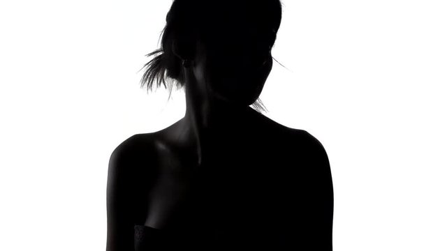 Silhouette of woman with wind in hair, turning her head from one side to another, shot in slow motion