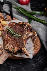 Tomahawk steak with vegetables and a knife on the table. Grilled meat with grilled vegetables and fresh vegetables on the table.