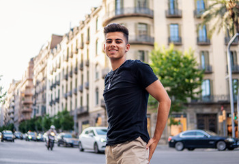 Young fashionable handsome man on the street of modern city. He looks happy and smiling