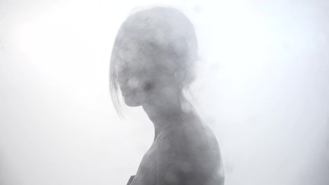 Silhouette of woman with dew drops of rain on glass, focus transition