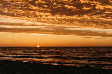 Beautiful sunset over the Baltic Sea shoreline. Jelenia Gora, Poland. Clouds lighten up from below. 