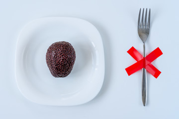 not peeled avocado on the white plate with fork on the table. Time to eat, Breakfast, Lunch time and dinner concept. Diet concept.