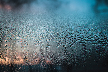 Raindrops on the surface of window panes with a cloudy background and sunlight