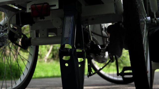 Cyclist in blue rubber gloves is cleaning the electric bicycle back wheel outside in the summer day. Slow motorized dolly shot motion, Close up slider trucking side movement from below. 4k