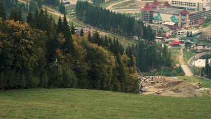 Two people rides an speed attraction Zip line or flying fox in mountain landscape, resort Bukovel, back view, 4k - Powered by Adobe