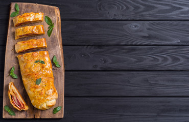 Pizza roll stromboli with cheese salami olives and tomatoes