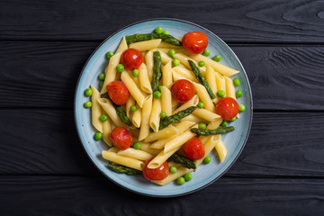 Penne pasta salad with asparagus , tomatoes and peas