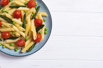 Penne pasta salad with asparagus , tomatoes and peas