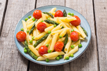 Penne pasta salad with asparagus , tomatoes and peas