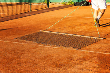 Obraz premium Preparing a tennis court for the match. Man aligns ground cover.